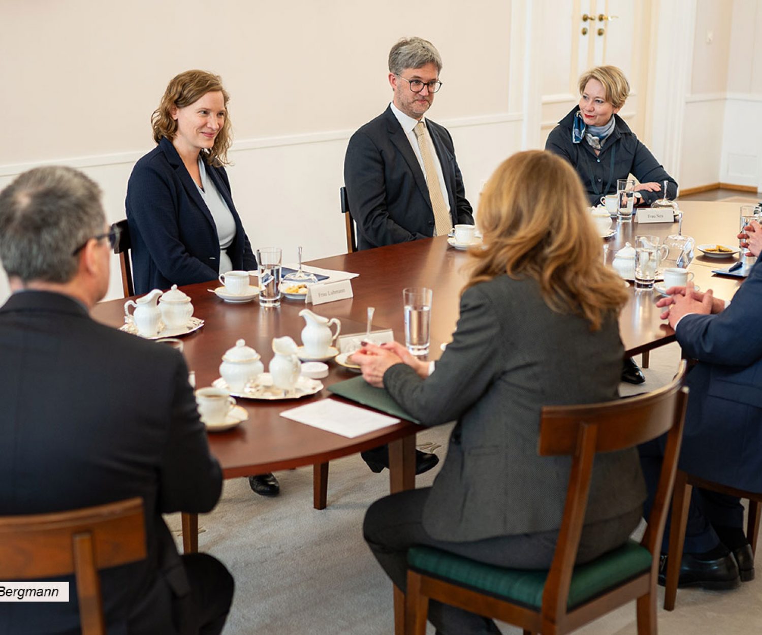Gesprächsrunde mit etwa 10 Personen an einem ovalen Tisch.